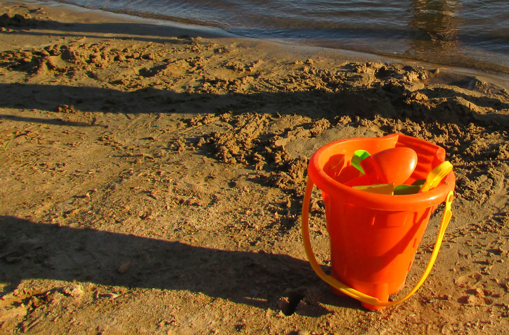 Kids orange sand bucket on beach